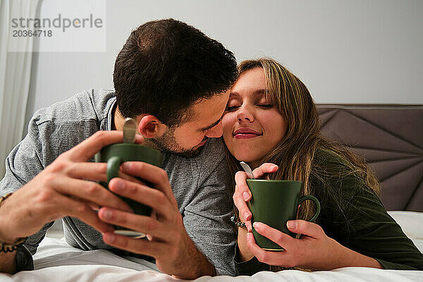 Verliebtes spanisches Paar trinkt Kaffee im Bett.