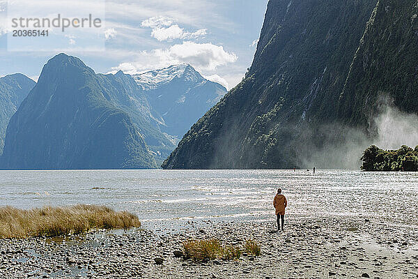 Mädchen steht am Rande der natürlichen Landschaft von Milford Sound in Neuseeland