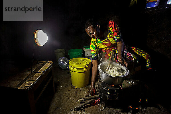 Tansanischer Mann bereitet Abendessen mit Ugali  Gemüse und Bohnen zu