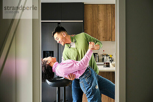 Multiethnisches glückliches Paar tanzt in der Küche.