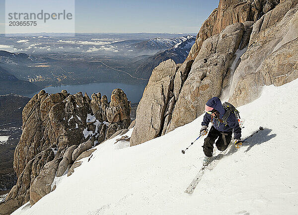 In der Ferne ist ein Mädchen auf Telemark-Ski in den Anden mit der Stadt Bariloche zu sehen
