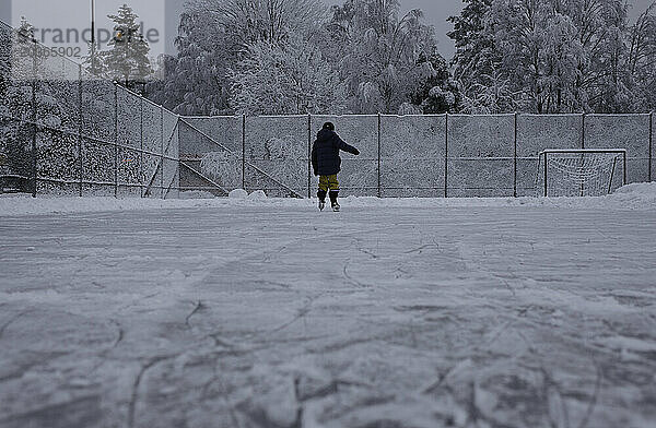 Kind beim Eislaufen draußen in ihrem Garten in Schweden