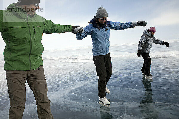 Drei Personen Eislaufen auf dem zugefrorenen Baikalsee  Sibirien  Russland.