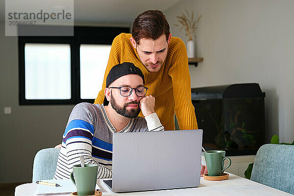 Homosexuelles Paar macht sich Sorgen oder ist langweilig  wenn es zu Hause den Laptop benutzt.