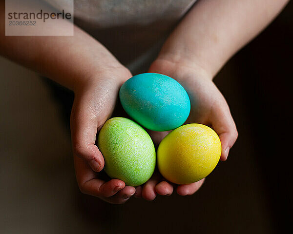 Kind hält drei farbige Eier
