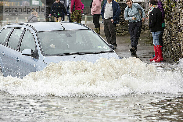 Auto fährt tief im Wasser in überfluteter Straße in Storth an der Flussmündung des Kent