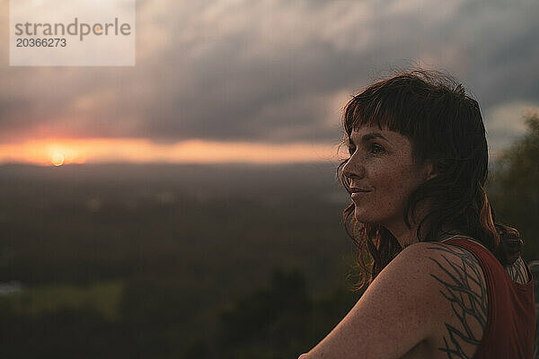 Eine Frau blickt friedlich auf den Sonnenuntergang in Queensland