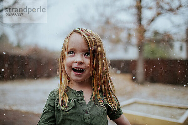 Lächelnder Vorschulkind  der draußen im Schnee spielt