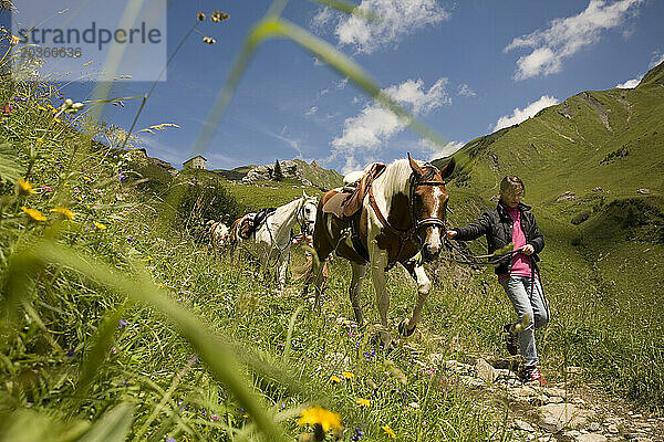 Mädchen gehen mit ihren Pferden in den französischen Alpen spazieren.