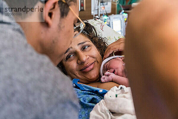 Indische Mutter lächelt Papa nach der Geburt im Krankenhaus an