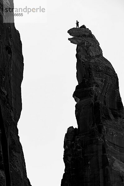 Niedrigwinkelaufnahme eines Bergsteigers  der auf dem Gipfel einer felsigen Klippe steht