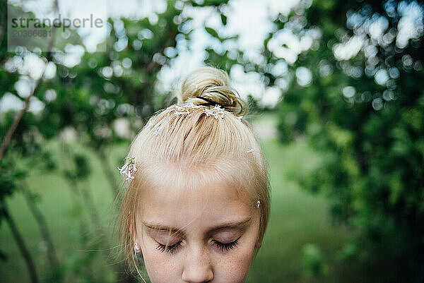 Porträt eines Mädchens mit Blütenblättern im Haar im Frühling im Freien