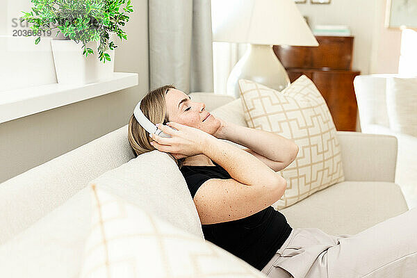 Frau in ruhiger häuslicher Umgebung hört Musik über Kopfhörer