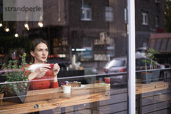 Außenansicht des Cafés mit einer jungen Frau  die drinnen am Fenster sitzt