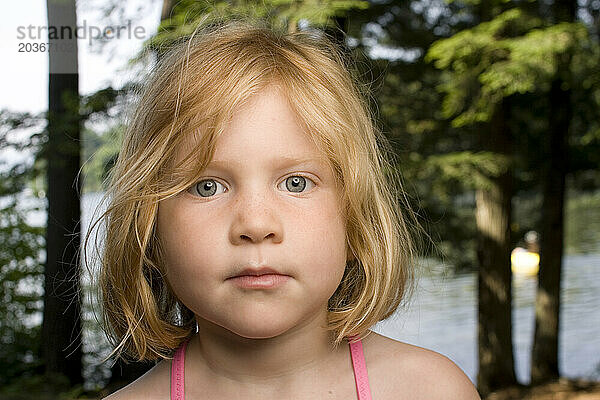 Ein junges rothaariges Mädchen  3-5 Jahre alt  posiert für ein Porträt im Freien.