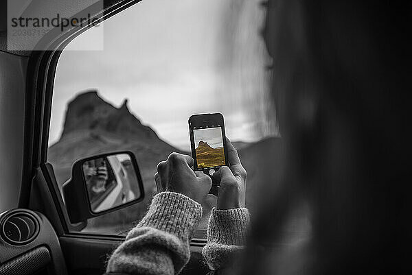 Frau fotografiert Berge vom Auto aus mit Handy