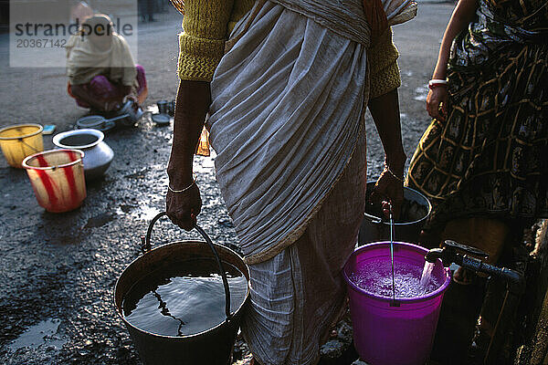 In Wohngebieten in Süd-/Zentral-Kalkutta  Indien  besuchen Frauen Röhrenbrunnen zum Baden  Waschen von Kleidung und zum Auffüllen von Wasser für Trink-/Haushaltszwecke.