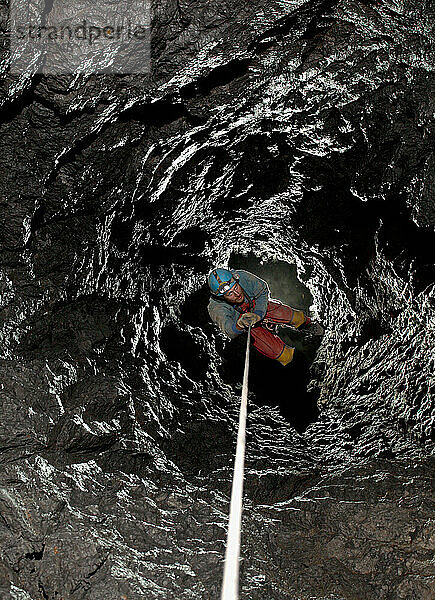 Höhlenforscher hängt in einem natürlich geformten Schacht in einer Höhle auf Kreta.