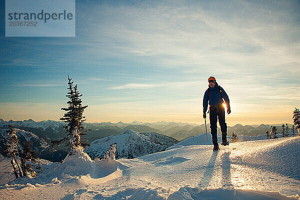 Silhouette eines Bergsteigers  der einen Bergrücken überquert