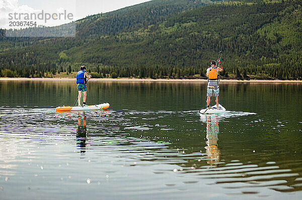 Zwei Paddleboarder genießen ein ruhiges Paddel auf einem ruhigen Bergsee
