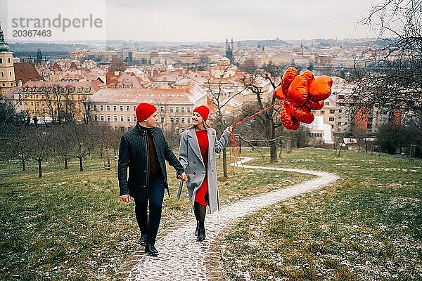 Junges Paar geht mit Luftballons im Herzen durch Prag