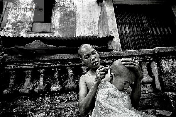 Mother shaves son's head in street  in Hanoi  Vietnam.