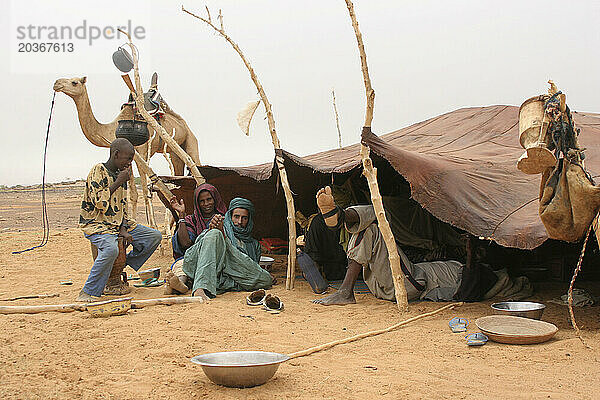 An African Islamic Toureg man ties up his camel and stops to rest at a nomadic encampment in the Sahel  Mali  West Africa