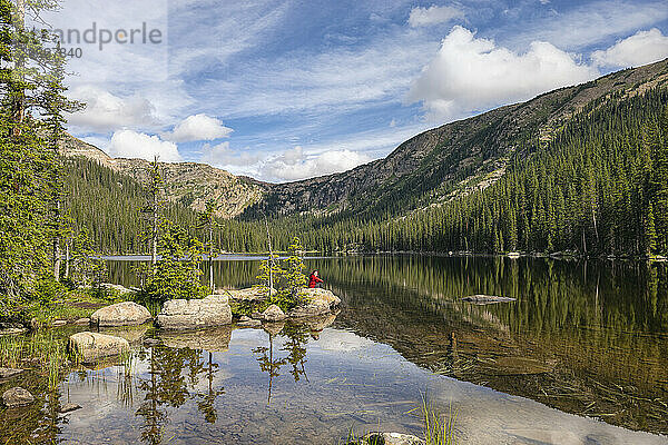 Einsamer Mensch an einem ruhigen See  umgeben von Bergen