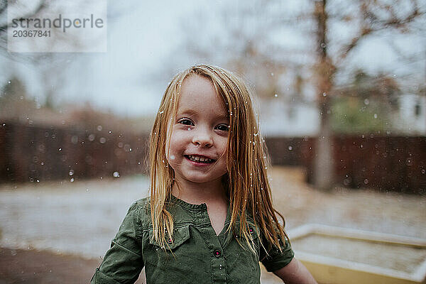 Glückliches junges Mädchen  das draußen im leichten Schnee steht