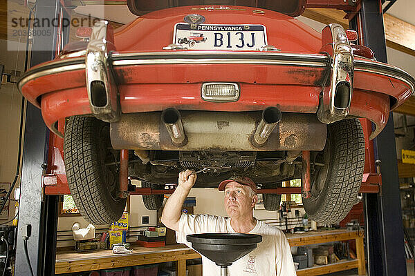 Ein Mann arbeitet in seiner Garage in Pennsylvania an seinem antiken Sportwagen.