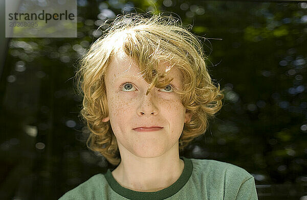 Ein kleiner Junge mit roten Haaren  8–10 Jahre alt  blickt lächelnd in die Kamera.