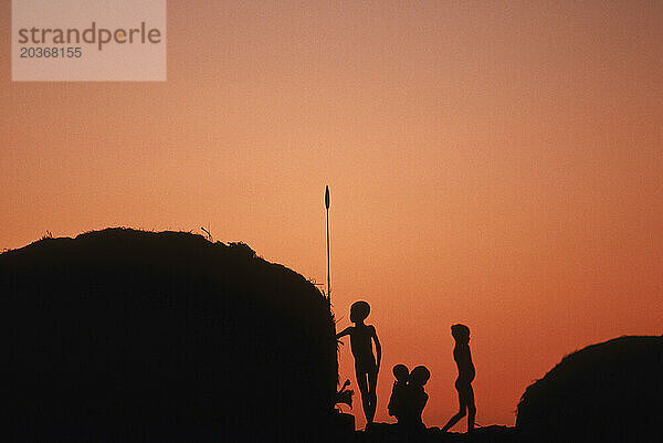 Silhouette kleiner Kinder in der Nähe der Hütten.