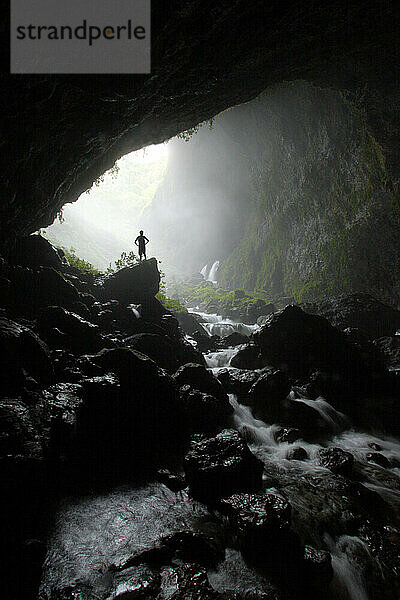 Ein Stammesangehöriger blickt in eine riesige Flusshöhle in New Britain