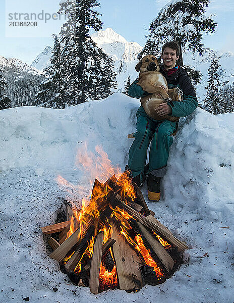 Mann und Hund entspannen sich am Feuer