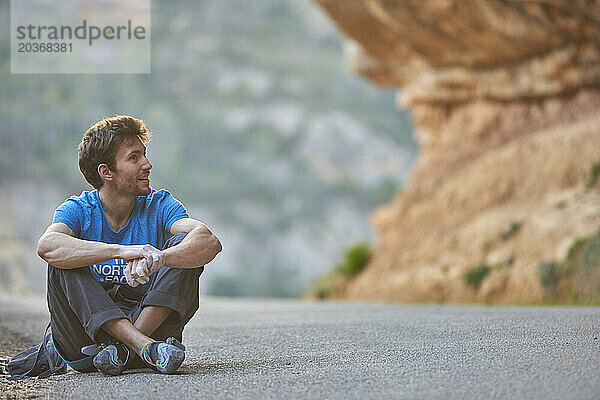 Kletterer sitzt im blauen T-Shirt und schaut von der Kamera weg  Margalef  Katalonien  Spanien