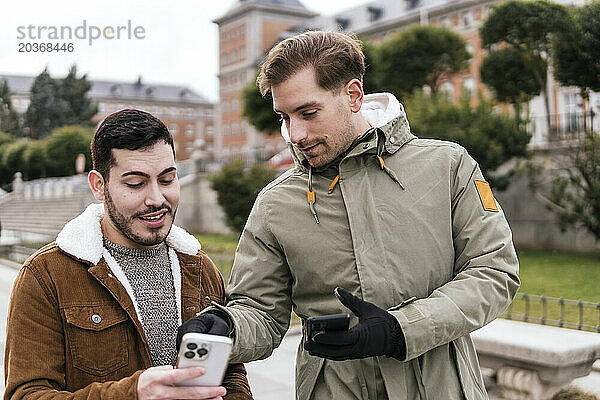 Zwei Freunde schauen auf der Straße auf das Handy