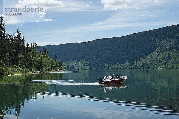 Blick auf drei Personen  die mit einem Motorboot auf dem See segeln  British Columbia  Kanada