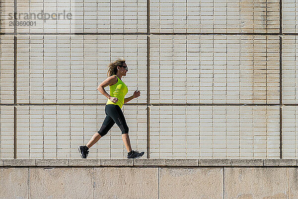 Erwachsene Frau läuft beim Training entlang einer weißen Musterwand