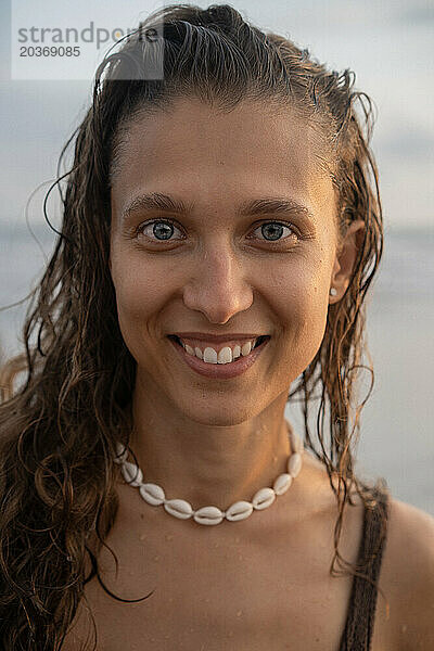 Porträt einer fröhlichen jungen Frau mit glücklichem lockigem Haar  die auf dem Meer läuft. Bali