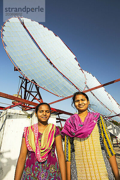 Zwei junge indische Frauen stehen gegen Solarheizungen