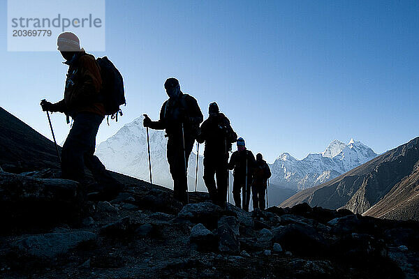 Silhouetten von Wanderern vor der Bergkulisse bei Sonnenaufgang über Dhugla  16.000 Fuß – Wanderung zum Berg. Everest-Basislager.