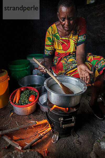 Tansanische Frau kocht Abendessen mit Ugali  Gemüse und Bohnen