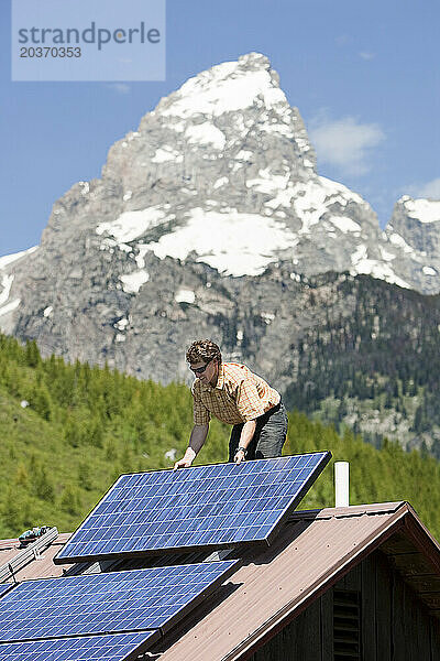 Ein Mann führt die Installation einer Photovoltaikanlage auf der Grand Teton National Park Climber's Ranch in Wyoming durch