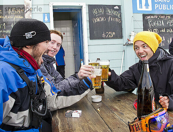 Drei Männer feiern einen fantastischen Skitag mit einem Bier am Cerro Catedral in Argentinien