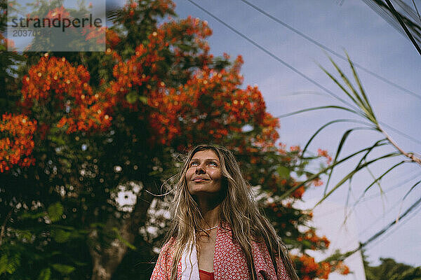 Junge Frau mit langen Haaren im Kimono geht auf Bali die Straße entlang.