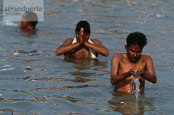 Männer beten und waschen sich im Hooghly River am Babu Ghat in Kalkutta  Indien. Der Fluss ist heilig  da das Wasser verschmutzt ist.