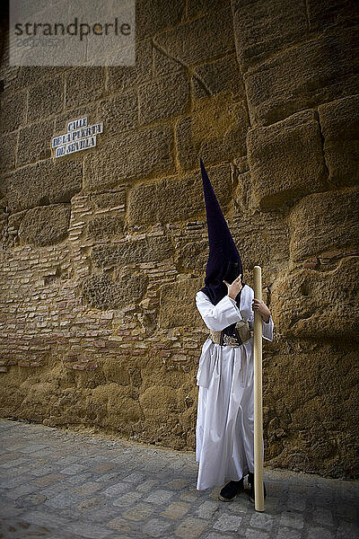 Ein Büßer hält eine Kerze während einer Prozession der Karwoche im Dorf Carmona  Provinz Sevilla  Andalusien  Spanien.