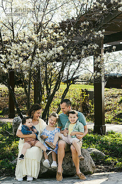 Familie lacht gemeinsam unter Frühlingsblütenbaum im Garten