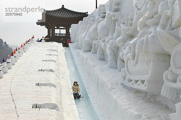 Asiatische Frau hat Spaß beim Rodeln steilen Eishangs  Hwacheon Sancheoneo Ice Festival  Gangwon-do  Südkorea