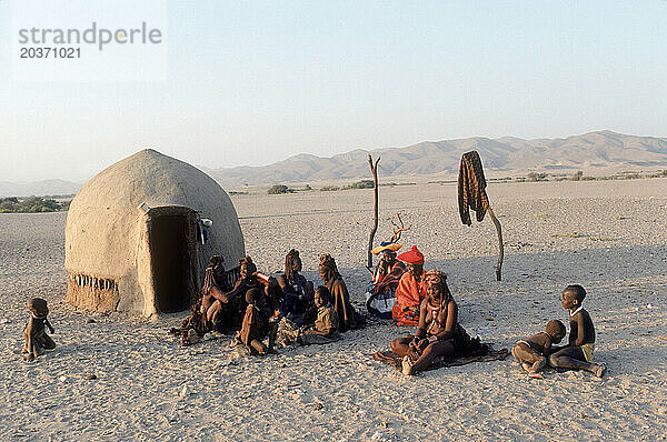 Himba-Leute sitzen vor einer Hütte in ihrem Dorf  Namibia.